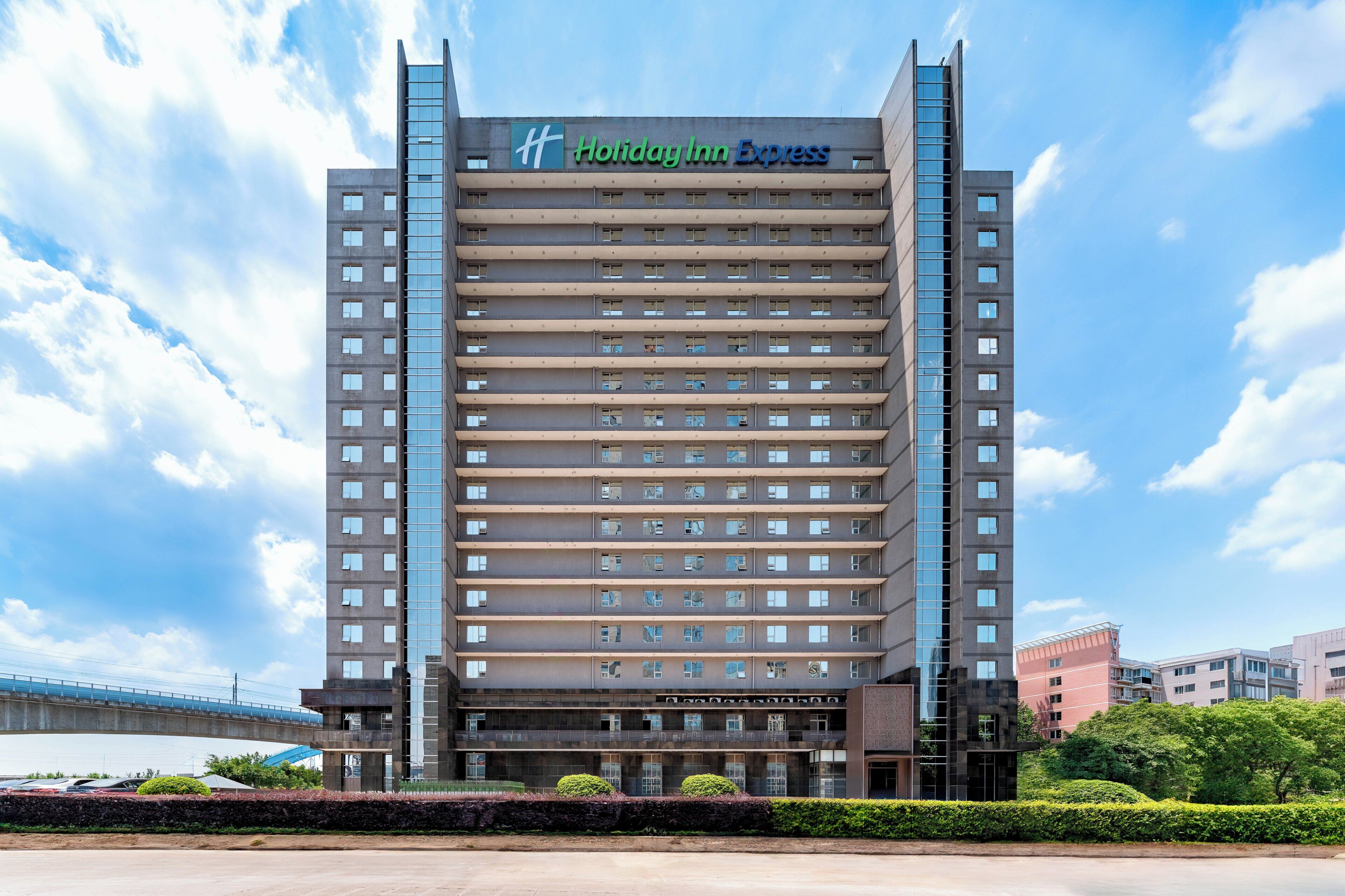 A multi-story hotel with a prominent 'Holiday Inn Express' sign, featuring a modern architectural design with a flat facade and numerous windows.