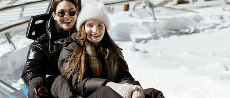 Two people on a sled in a snowy outdoor setting.