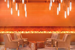 A lobby with two armchairs, a round wooden table, and hanging pendant lights.