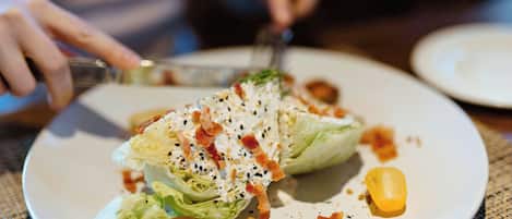 A plate with a salad, a fork, and a knife on a table.