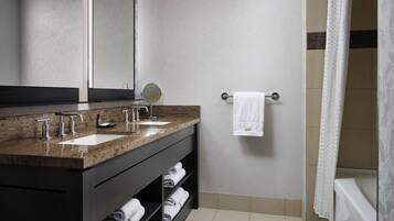 Un baño moderno con encimera de granito, dos lavamanos, un espejo y un perchero para toallas.