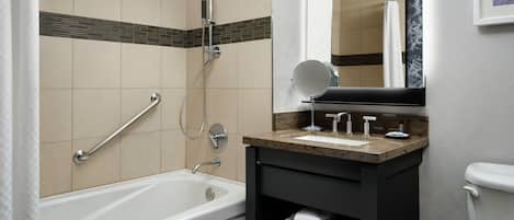 Un baño moderno con bañera, ducha, lavamanos con espejo e inodoro.