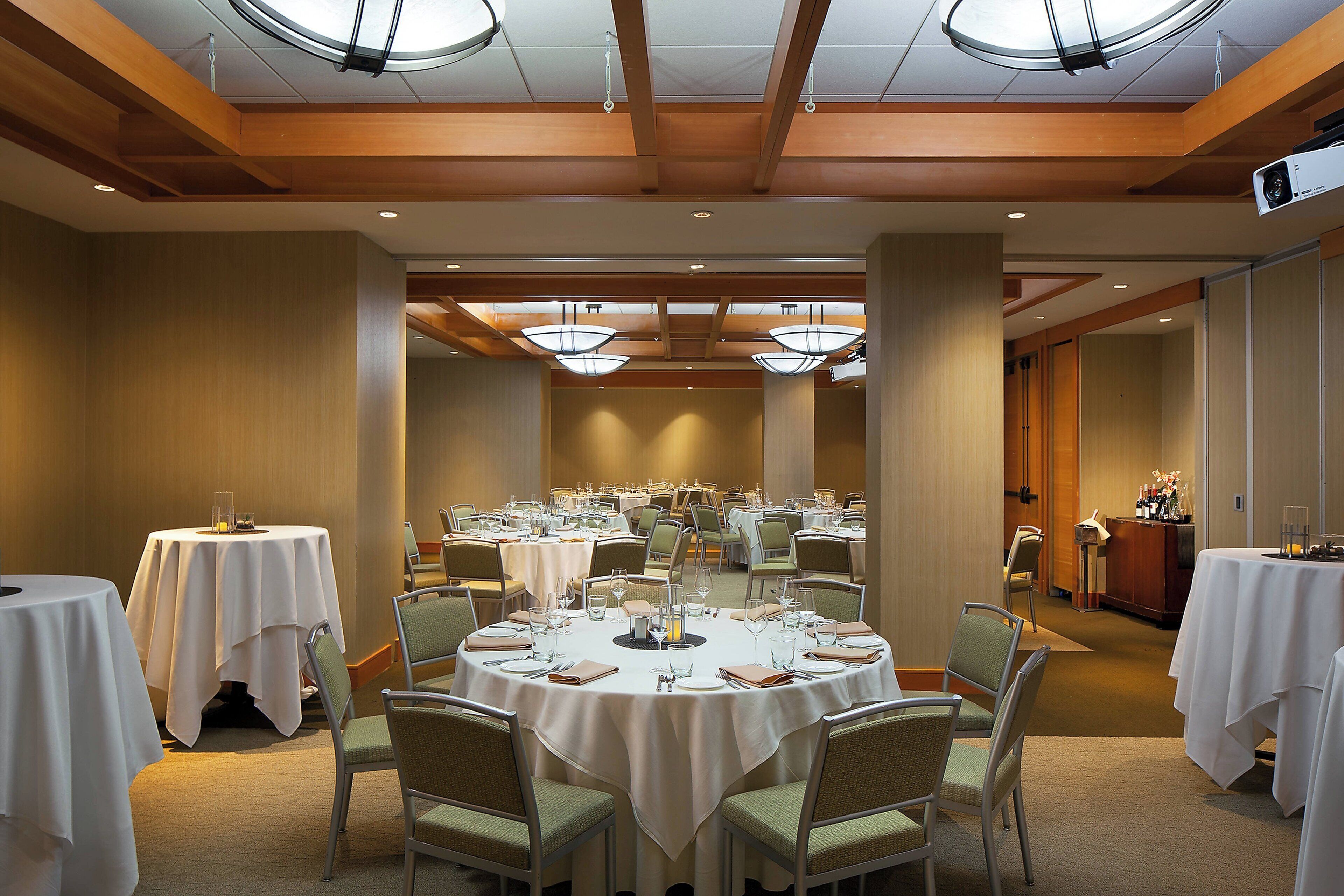 A conference room with round tables, chairs, and a projector screen.