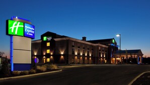 A Holiday Inn Express & Suites hotel with a prominent sign, brick exterior, and well-lit entrance.