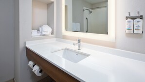 A bathroom with a white sink, a mirror, and a shelf with towels and Dove toiletries. - Holiday Inn Express Hotel & Suites Athens by IHG (Athens)