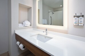 Een badkamer met een wit wastafel, een spiegel en een plank met handdoeken en Dove toiletartikelen.
