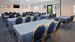 A conference room with multiple tables and chairs, a flat-screen TV on the wall, and framed artwork on the walls. - Holiday Inn Express Hotel & Suites Athens by IHG (Athens)
