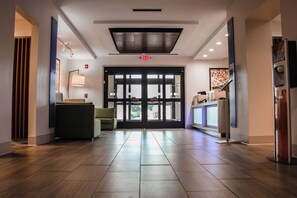 A hotel lobby with a reception desk, seating area, and a large glass door leading outside. - Holiday Inn Express Hotel & Suites Athens by IHG (Athens)