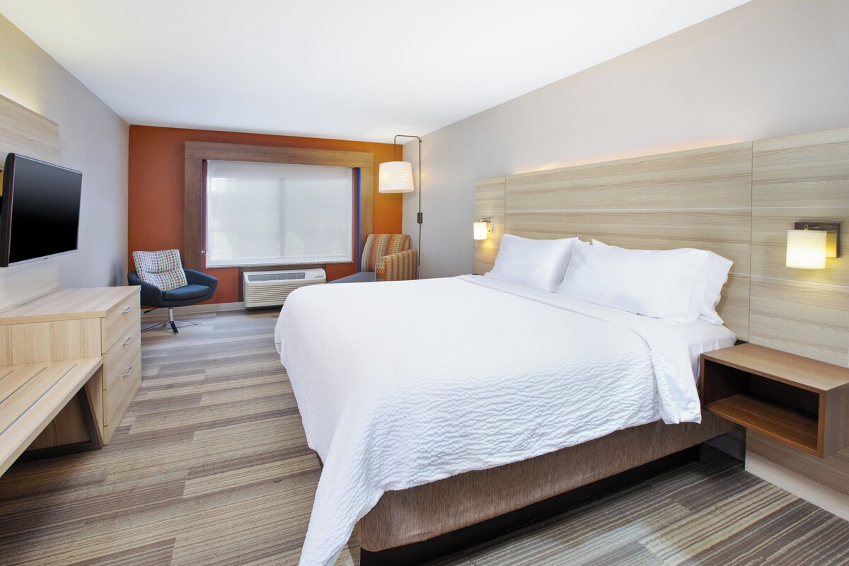 Een hotelkamer met een groot bed, een bureau, een stoel, een televisie en een raam.