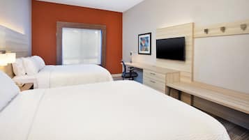 A hotel room with two beds, a desk, a chair, a TV, and a window.