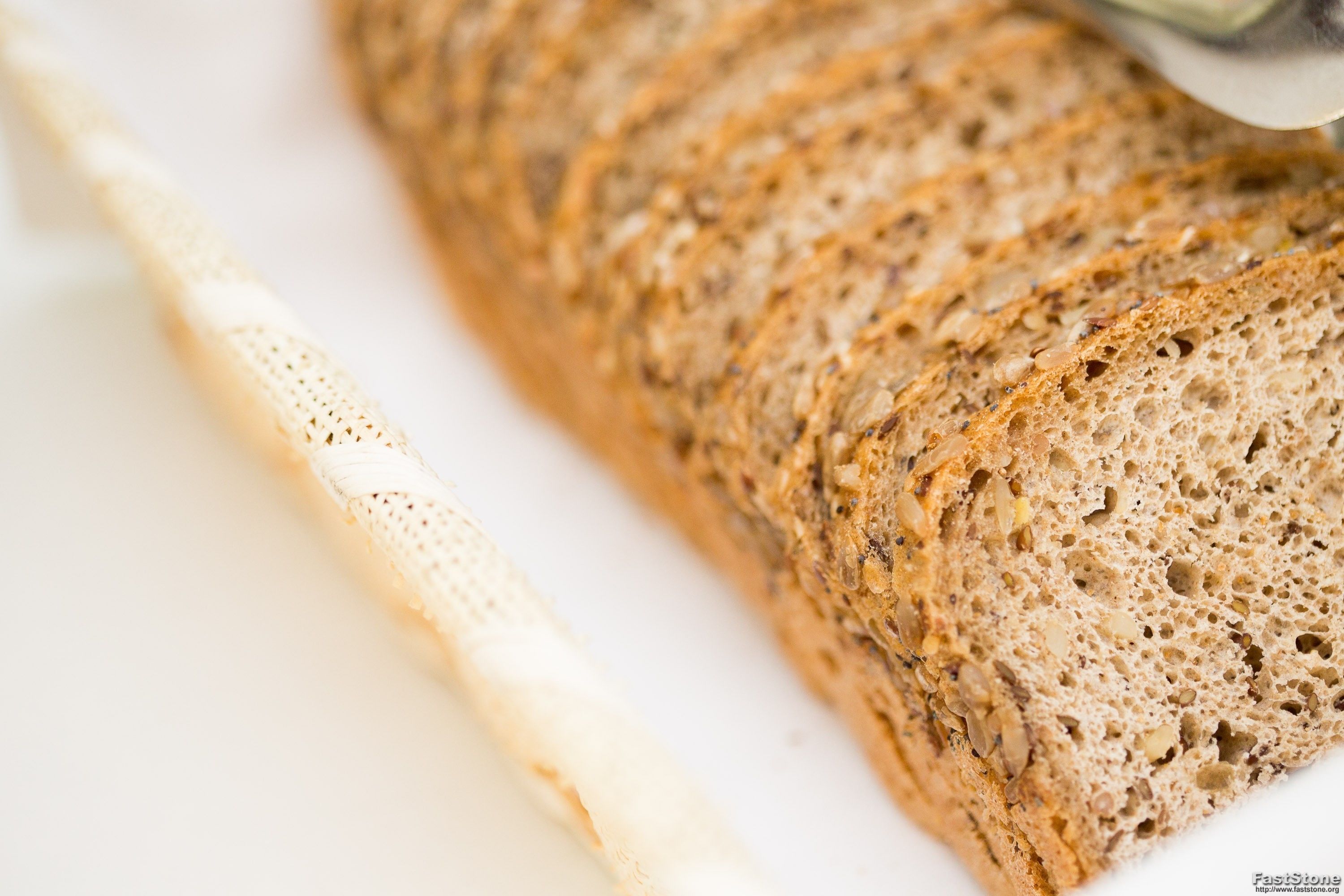 A loaf of sliced bread with a visible crust and seeds on a white plate.