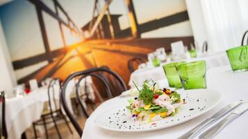 A restaurant setting with a white tablecloth, a plate of food, and a green glass.
