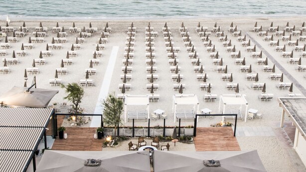 Un restaurante frente al mar con terraza al aire libre, una cubierta de madera y vistas al océano.