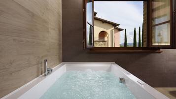 Ein modernes Badezimmer mit einer Badewanne, einem Fenster mit Blick auf ein Gebäude und einer Steinwand.