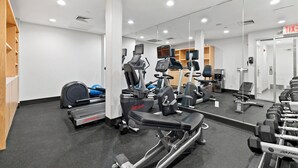 Une salle de sport équipée de machines de cardio, de bancs de musculation et d’haltères.