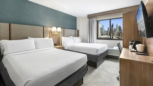 Une chambre d’hôtel avec deux lits, un bureau, une télévision et une vue sur la ville.