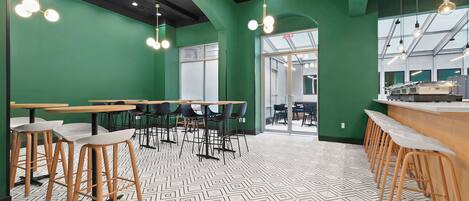 A modern cafe with green walls, wooden tables, and black and white patterned flooring.