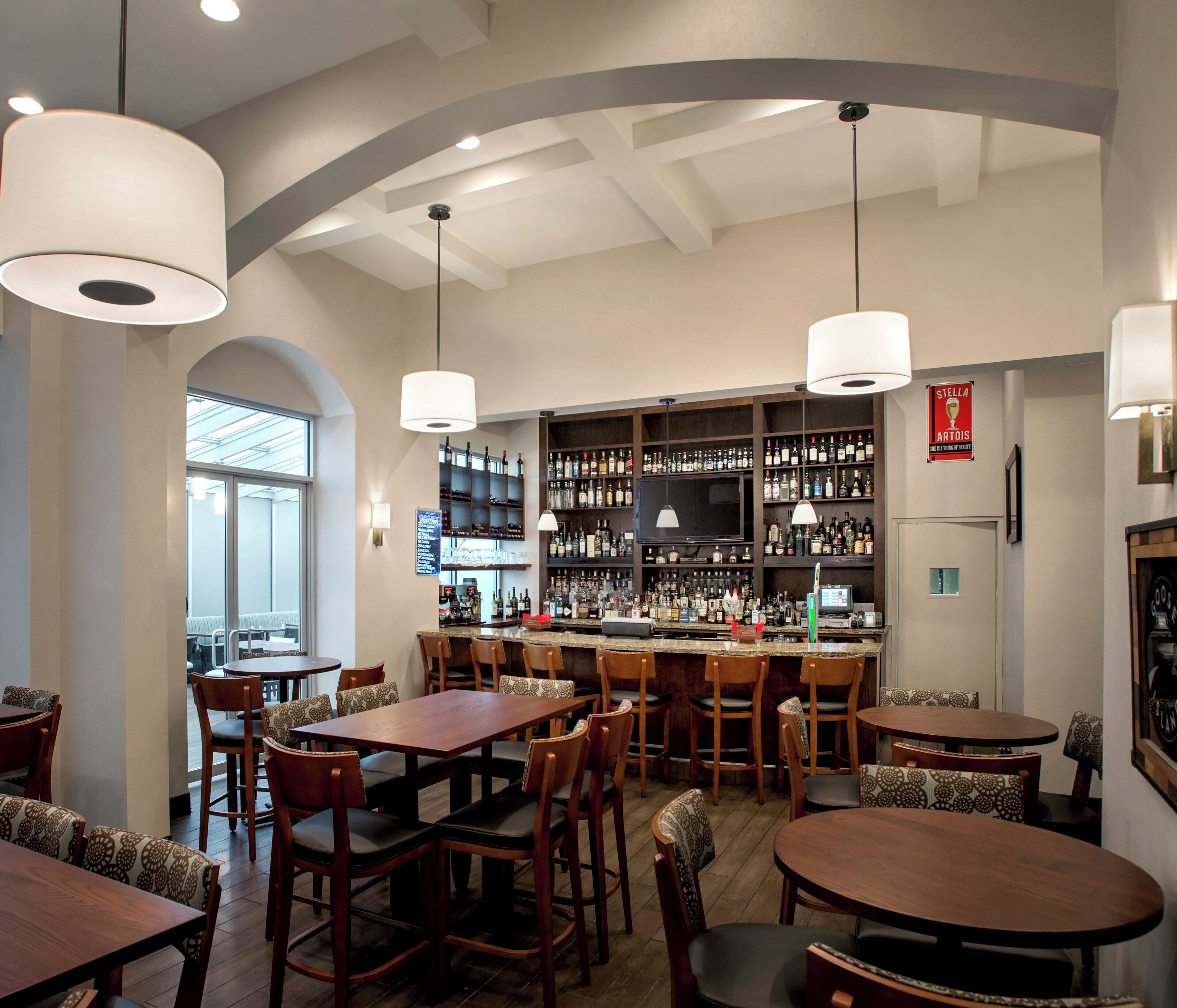 A bar area with multiple seating options, a television, and a variety of liquor bottles.