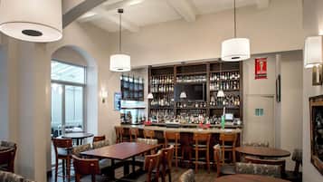 A bar area with multiple seating options, a television, and a variety of liquor bottles.
