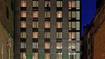 Un immeuble à plusieurs étages avec une entrée en verre, des drapeaux américains et l’enseigne Holiday Inn.