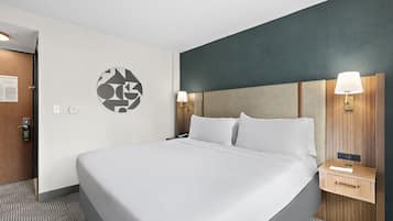 Une chambre d’hôtel avec un grand lit, une tête de lit en bois, deux lampes de chevet et une œuvre d’art accrochée au mur.