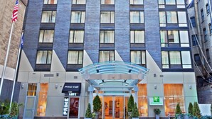 Un hotel alto con fachada moderna, que destaca por su entrada principal con una cubierta de vidrio.