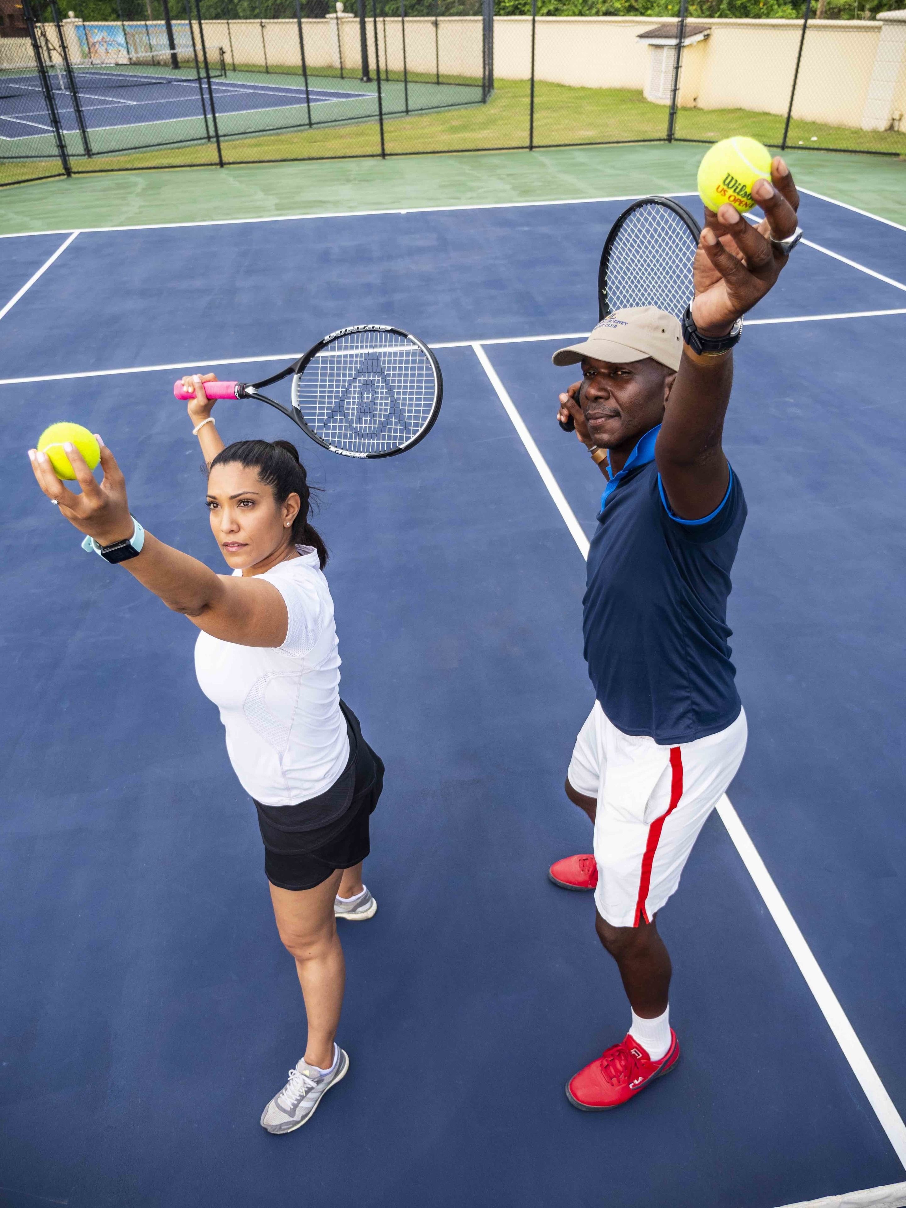 A tennis court with two people holding tennis balls and rackets.