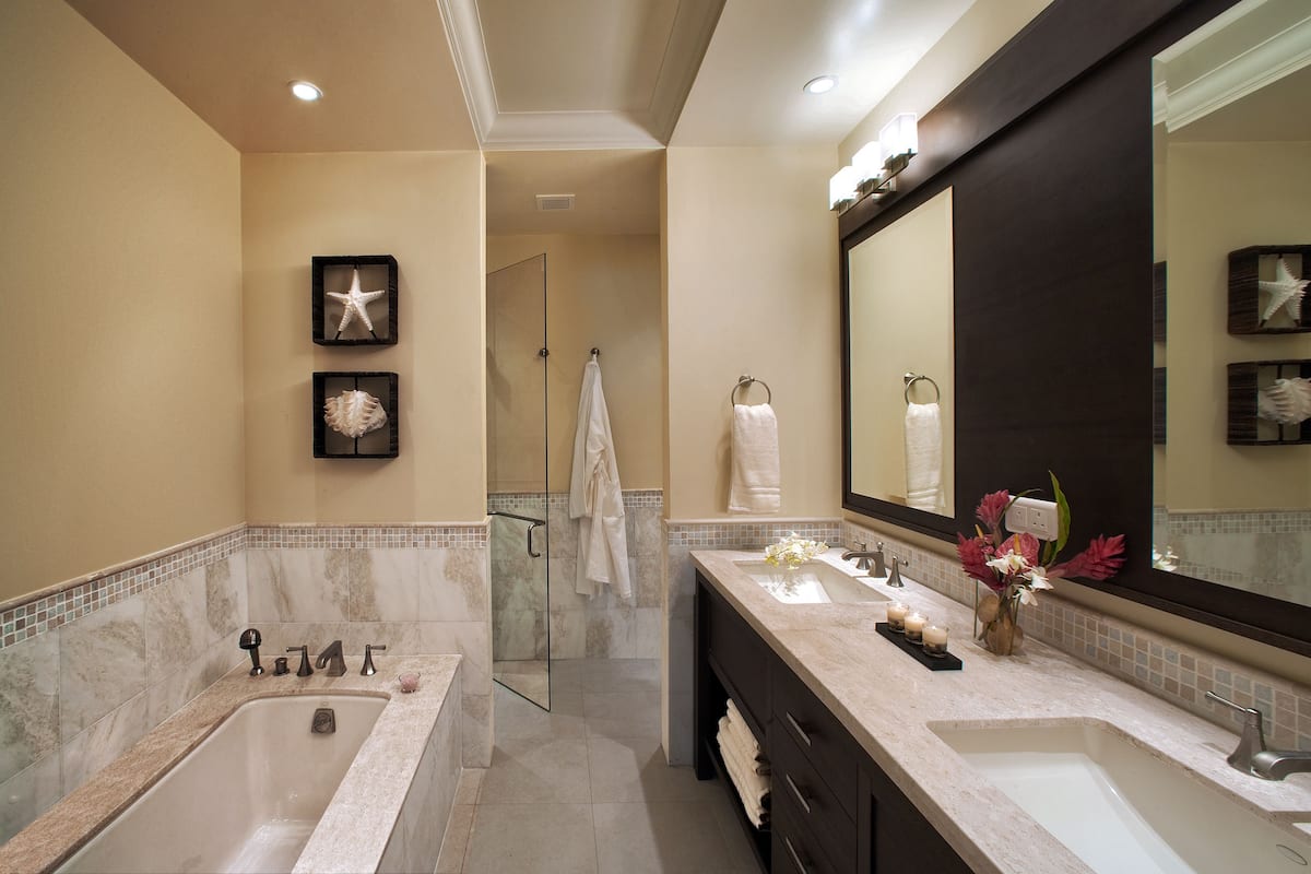 A modern bathroom with a large bathtub, two sinks, and a large mirror.