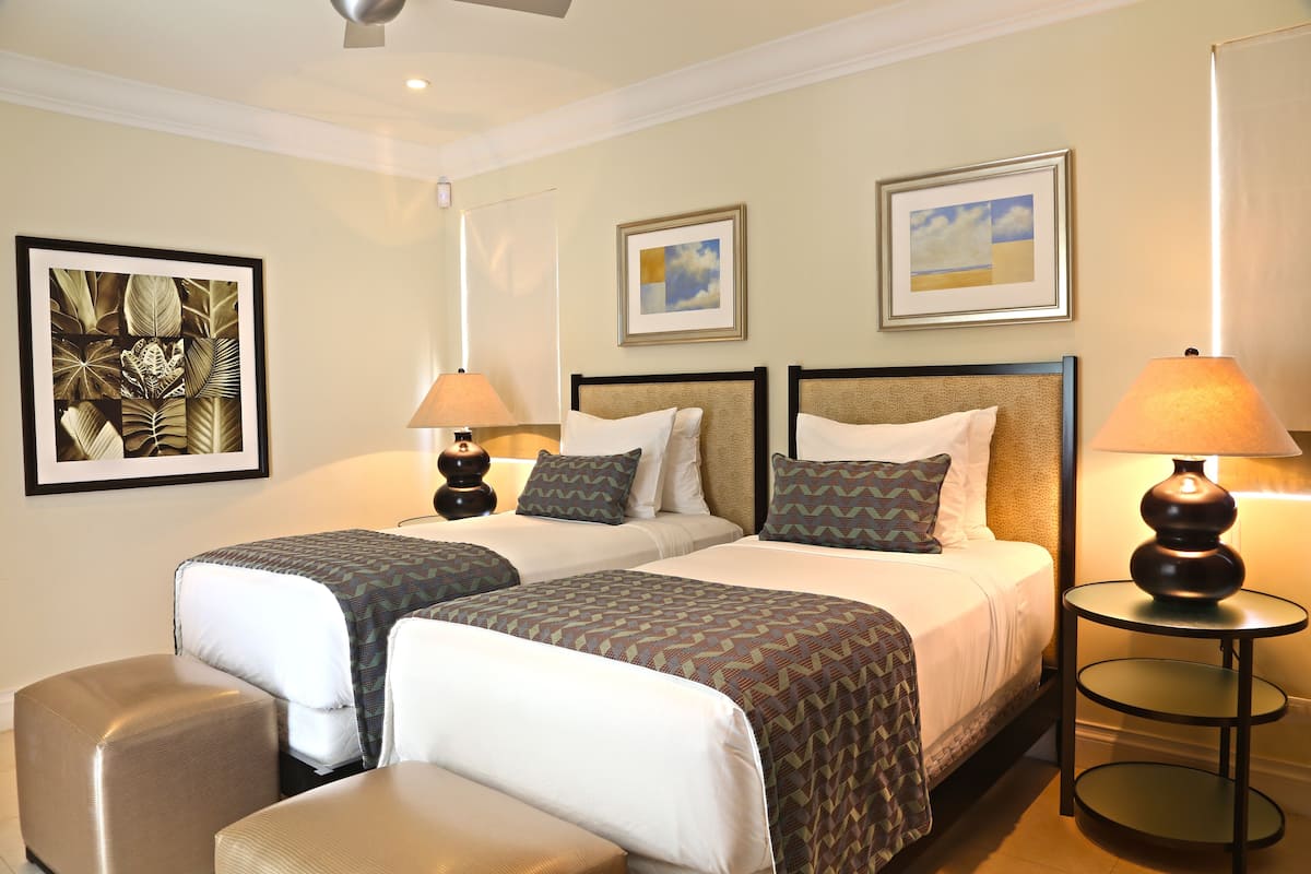 A hotel room with two beds, a small seating area, and artwork on the walls.
