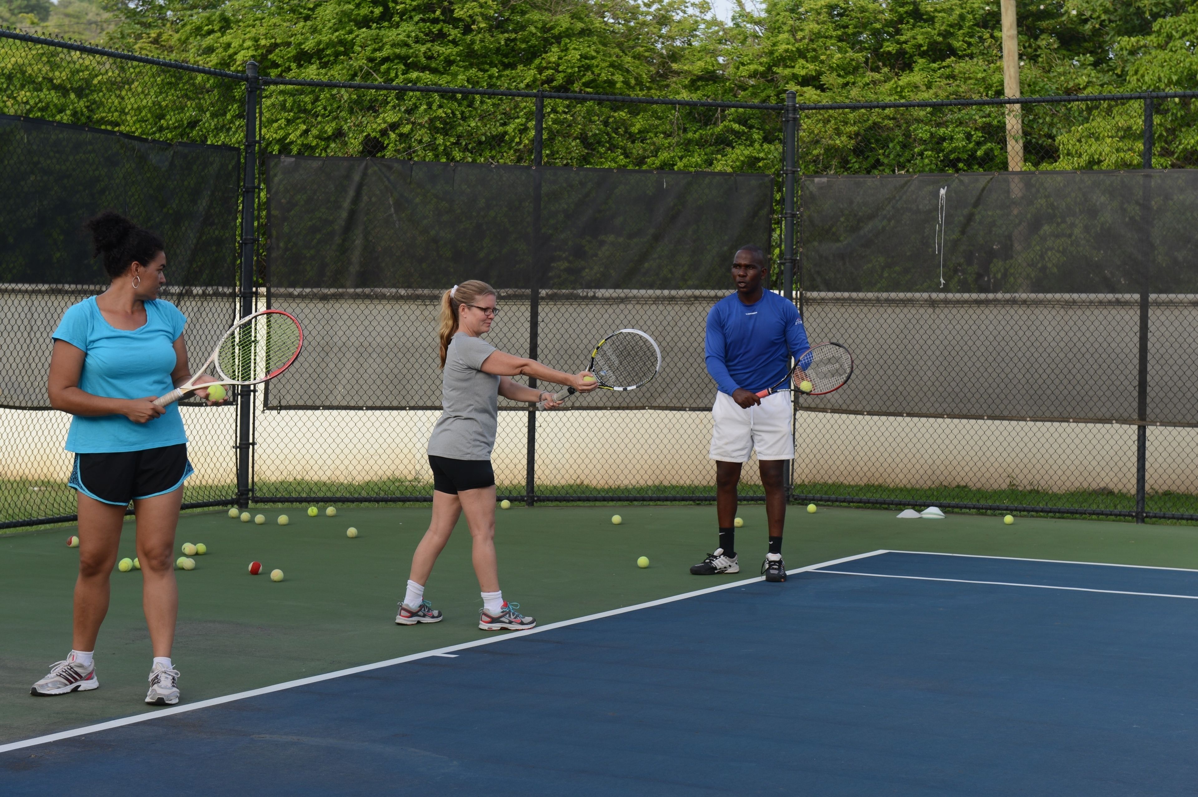 Una cancha de tenis con tres personas practicando.