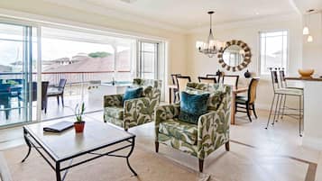 A spacious living area with a large window, a dining set, and a kitchen area.