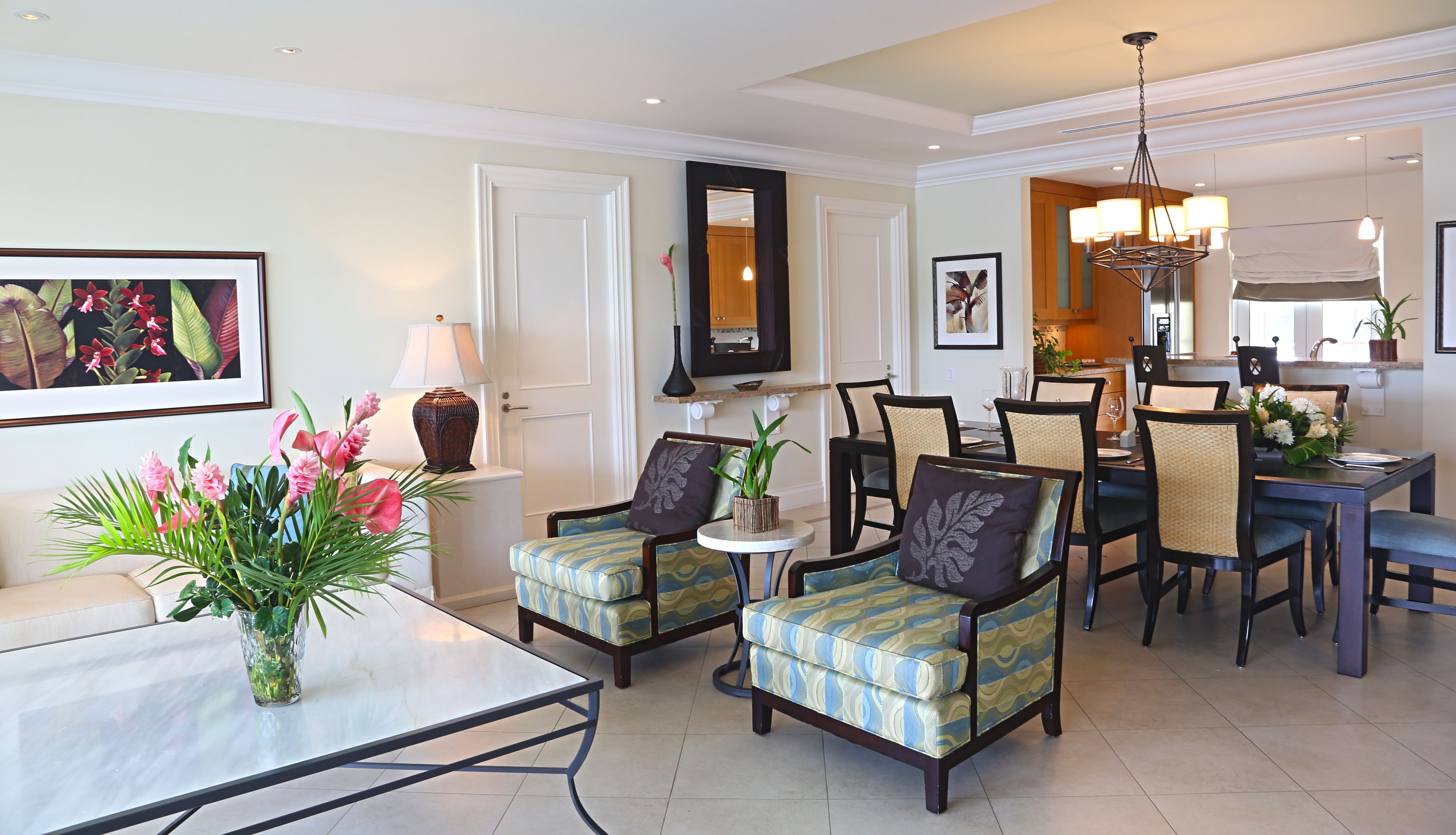 Een goed verlichte woonkamer met een eethoek, met een bank, fauteuils, een salontafel en een kroonluchter.