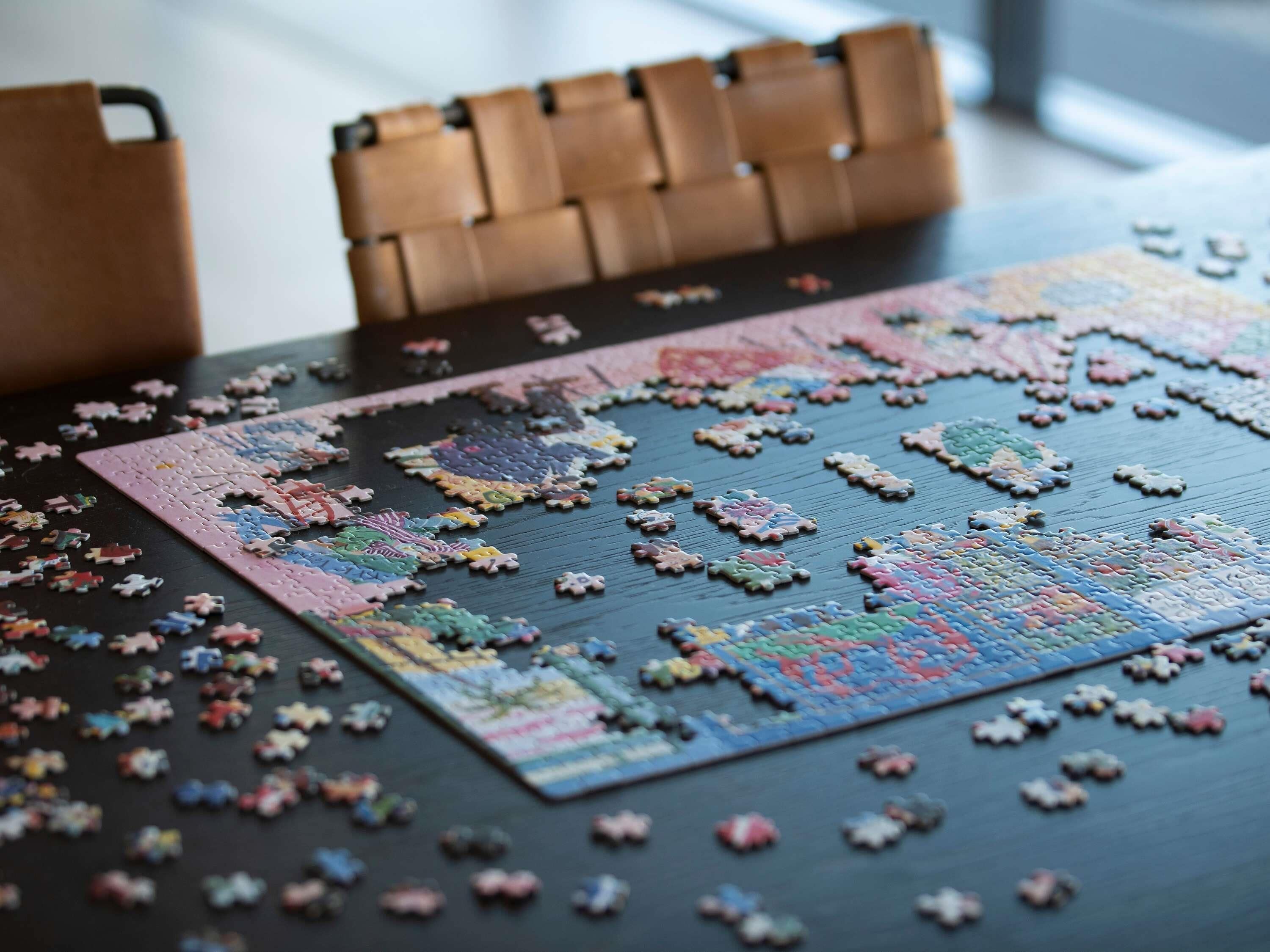 A puzzle on a table with pieces scattered around.