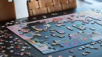 A puzzle on a table with pieces scattered around.