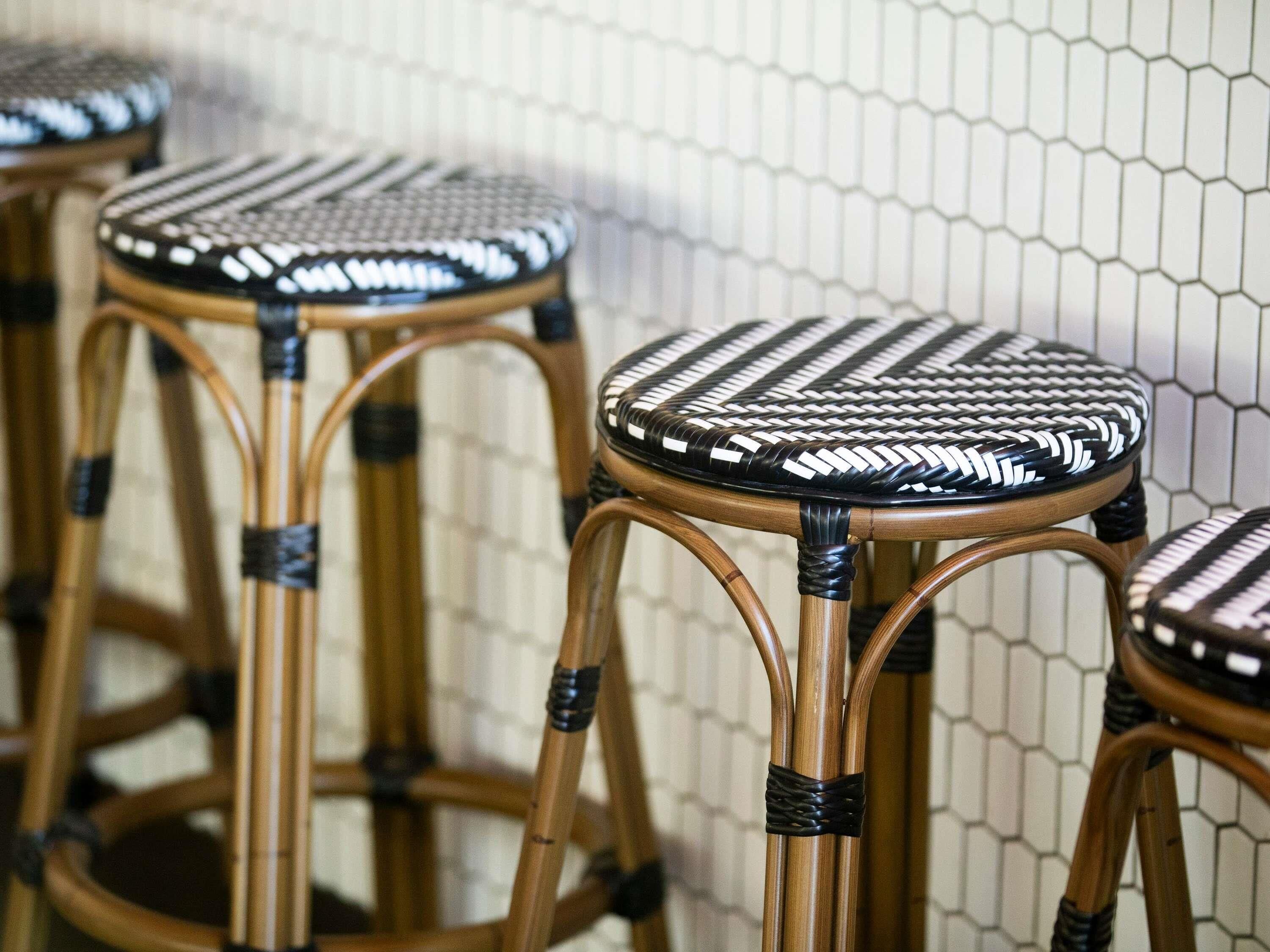 A close-up of a woven chair with a black and white pattern, part of a set of similar chairs.