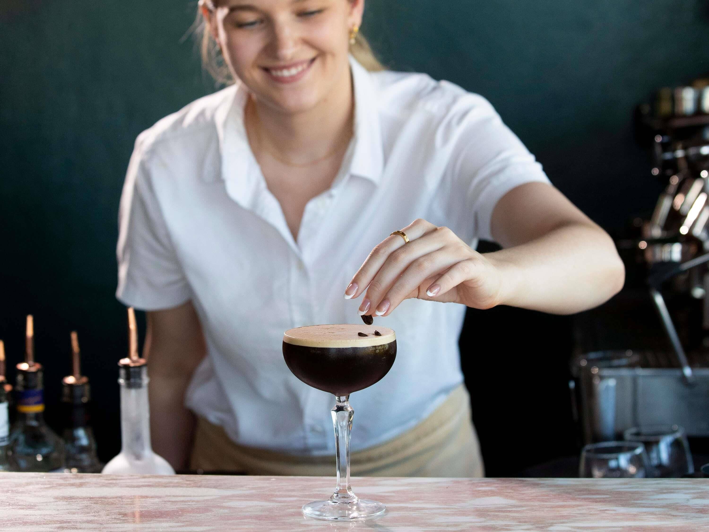 En person hælder drik i et glas.