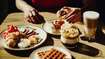 A table with various dishes including a waffle, a dessert with a berry topping, and a glass of milk.