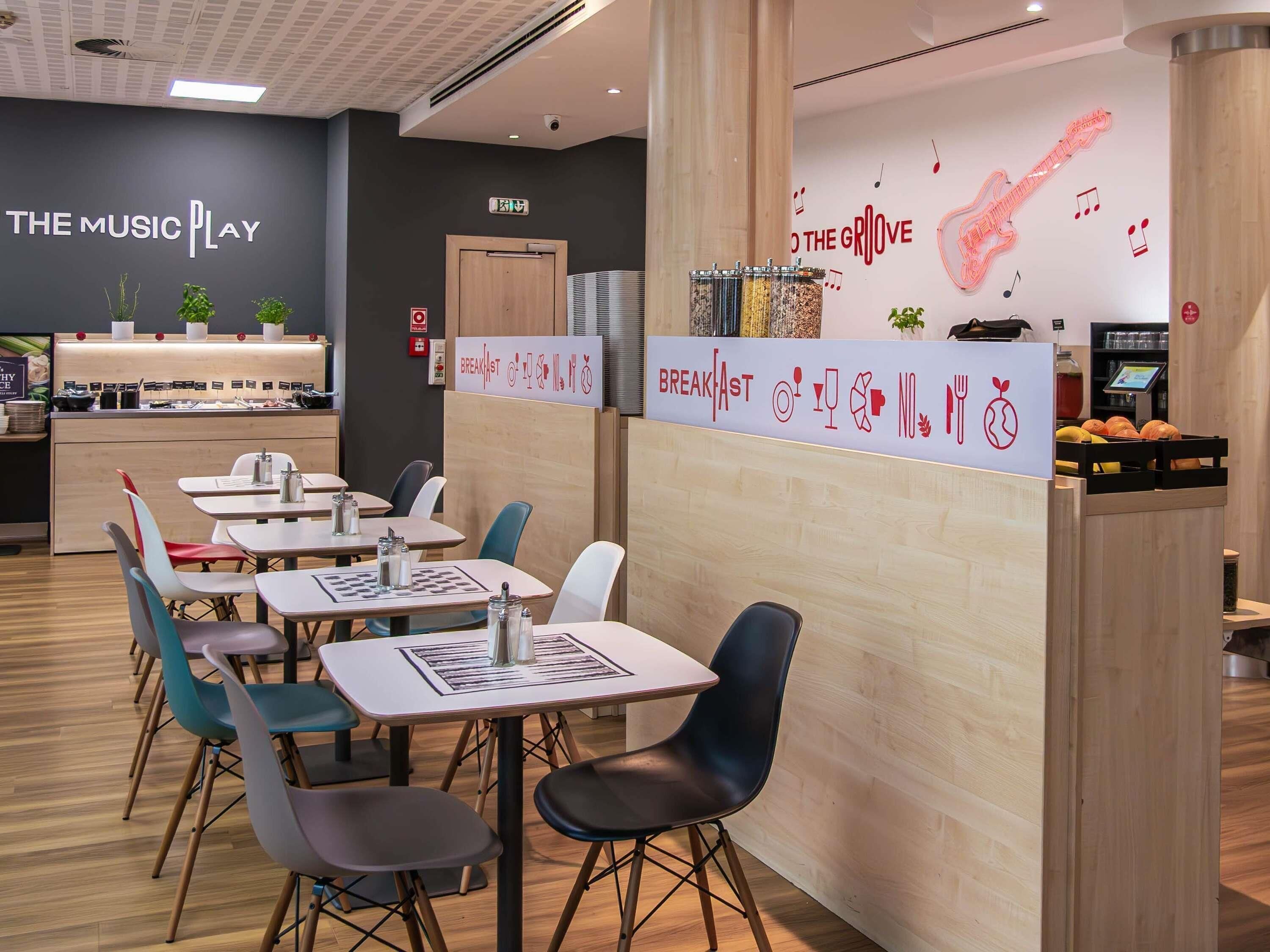 A restaurant with a breakfast section, tables, chairs, and a wall with musical notes and a guitar.