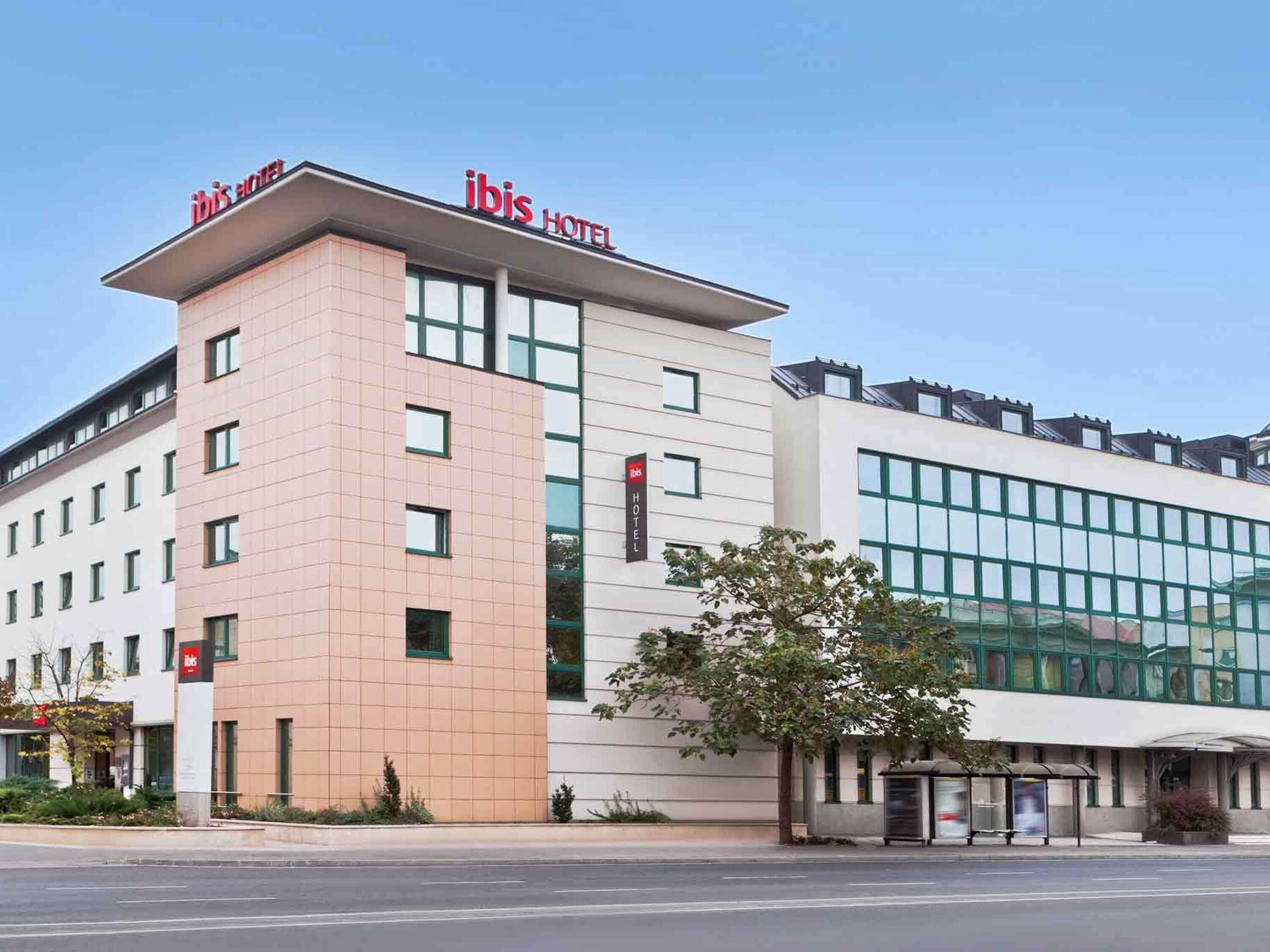 Un bâtiment d'hôtel moderne, avec une enseigne « IBIS HOTEL » bien visible, une façade en verre et un toit plat.