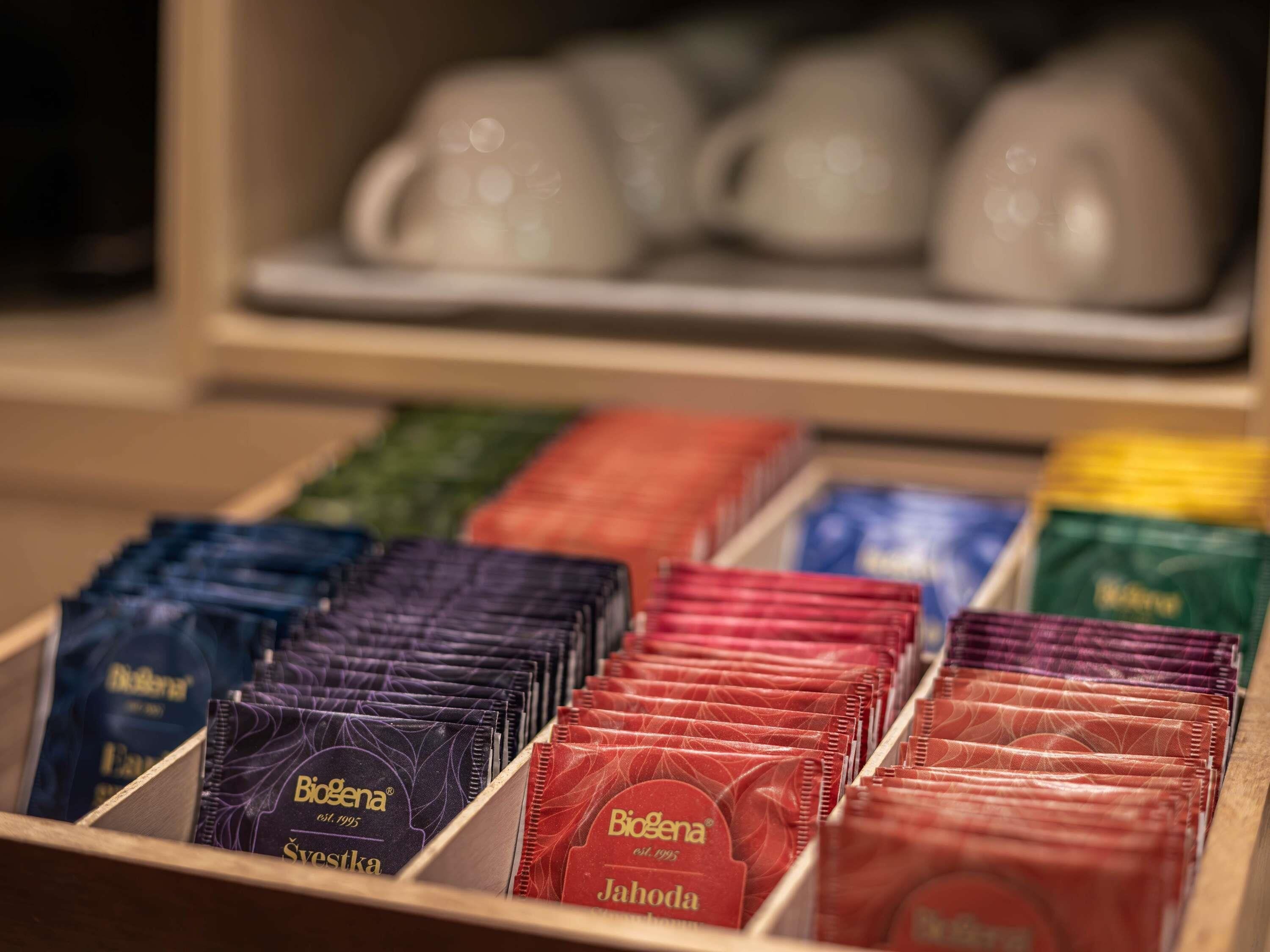Una exhibición de cajas de té Biogena en varios colores, dispuestas dentro de una caja de madera.
