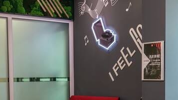 A modern interior with a red sofa, white chairs, a small table with a plant, and a wall with musical notes and the text "I FEEL SO".