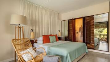 A bedroom with a bed, two bedside tables, a lamp, a chair, and a large mirror.