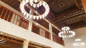 Un interno maestoso con lampadari decorati, ringhiere in legno e raffinate decorazioni al soffitto.