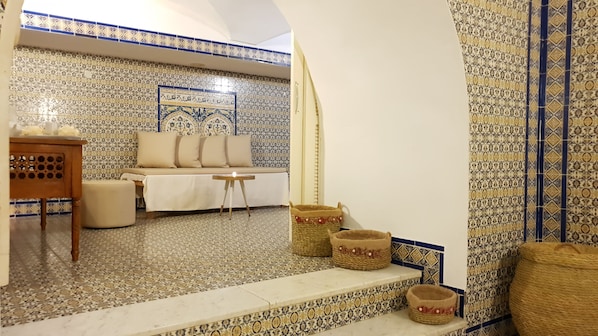 A cozy room with a patterned tile floor, a sofa with cushions, a small wooden table, and woven baskets.