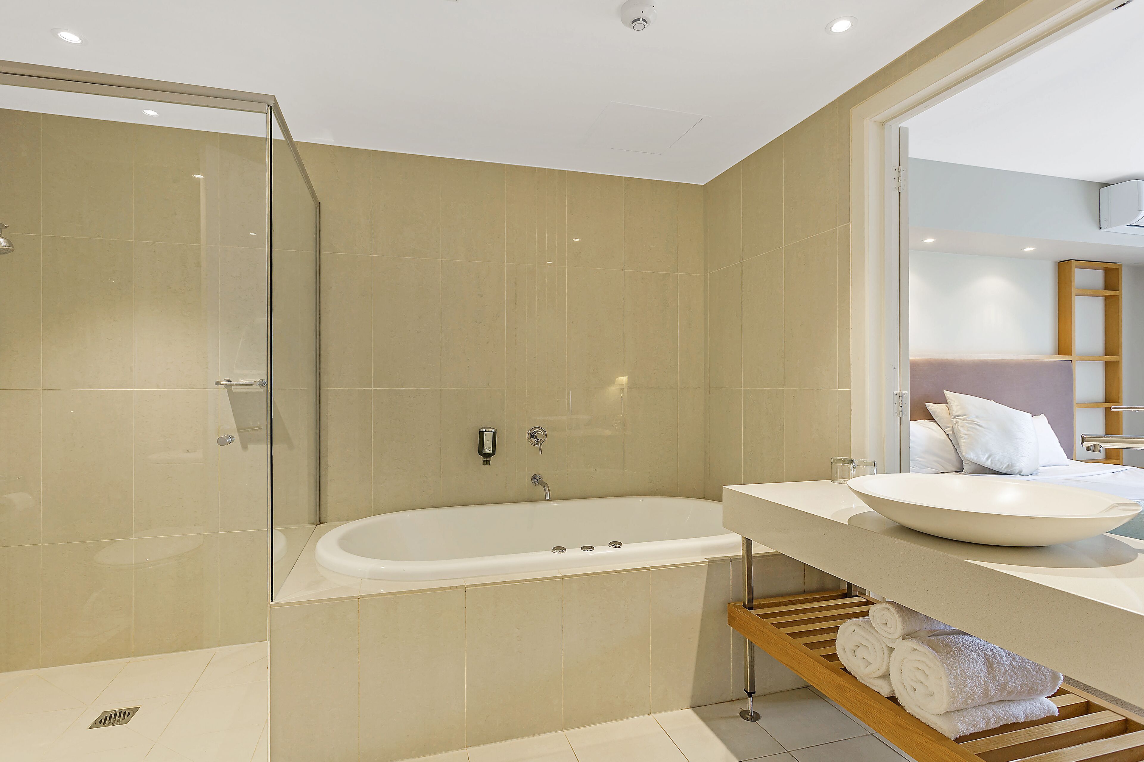 A modern bathroom with a glass-enclosed shower, a freestanding bathtub, and a vanity with a large sink and towel rack.