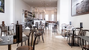 A spacious restaurant with wooden flooring, round tables, and modern chandeliers. - Deep Blue Hotel & Hot Springs (Warrnambool)
