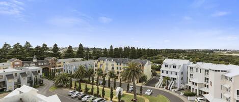 A residential area with modern apartment buildings, a parking lot, and a clear blue sky.