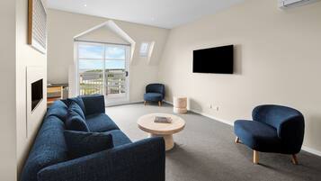 Una sala moderna con un sofá modular, una mesa de centro redonda y un sillón azul.