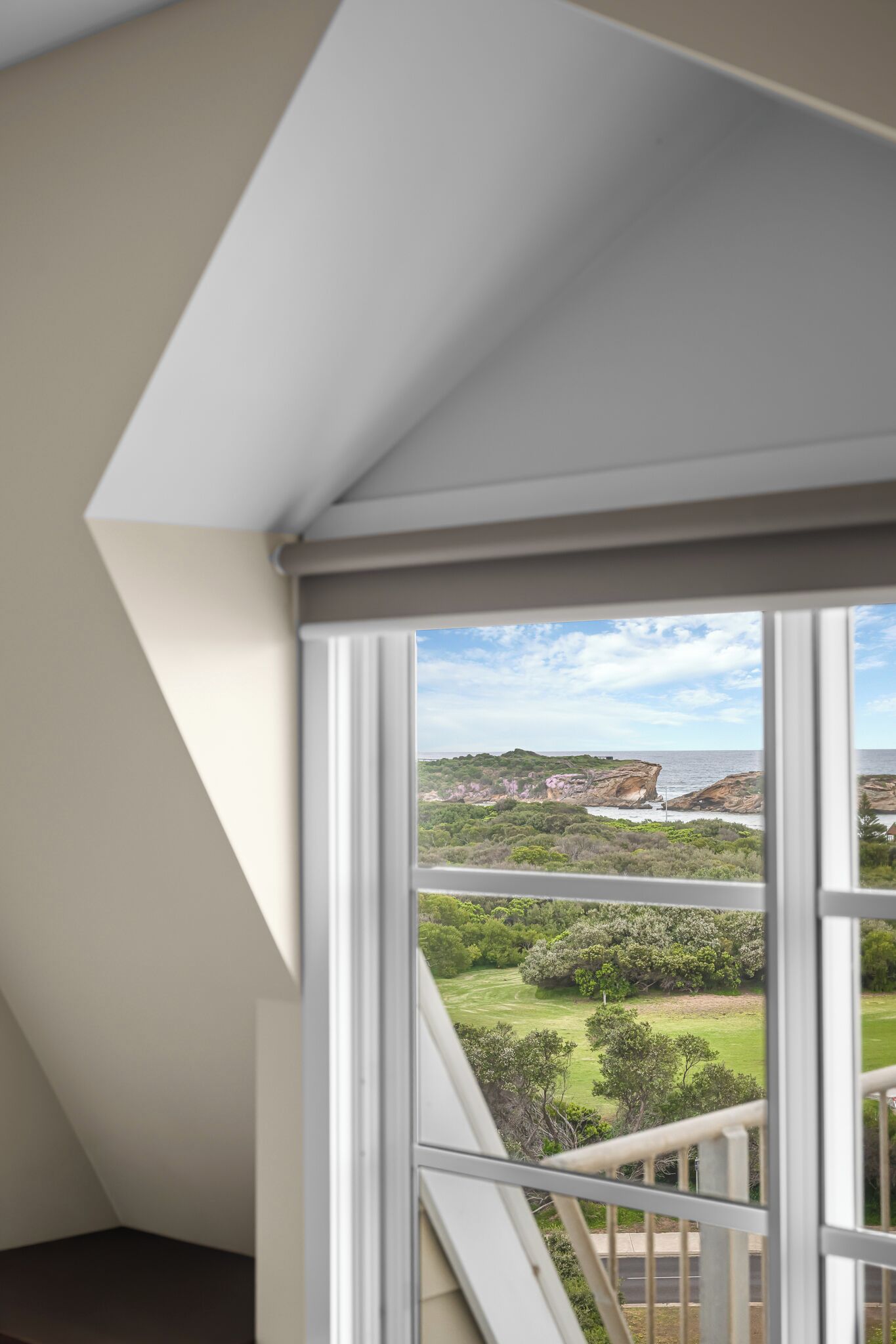 A room with a view of a coastal landscape through a large window.