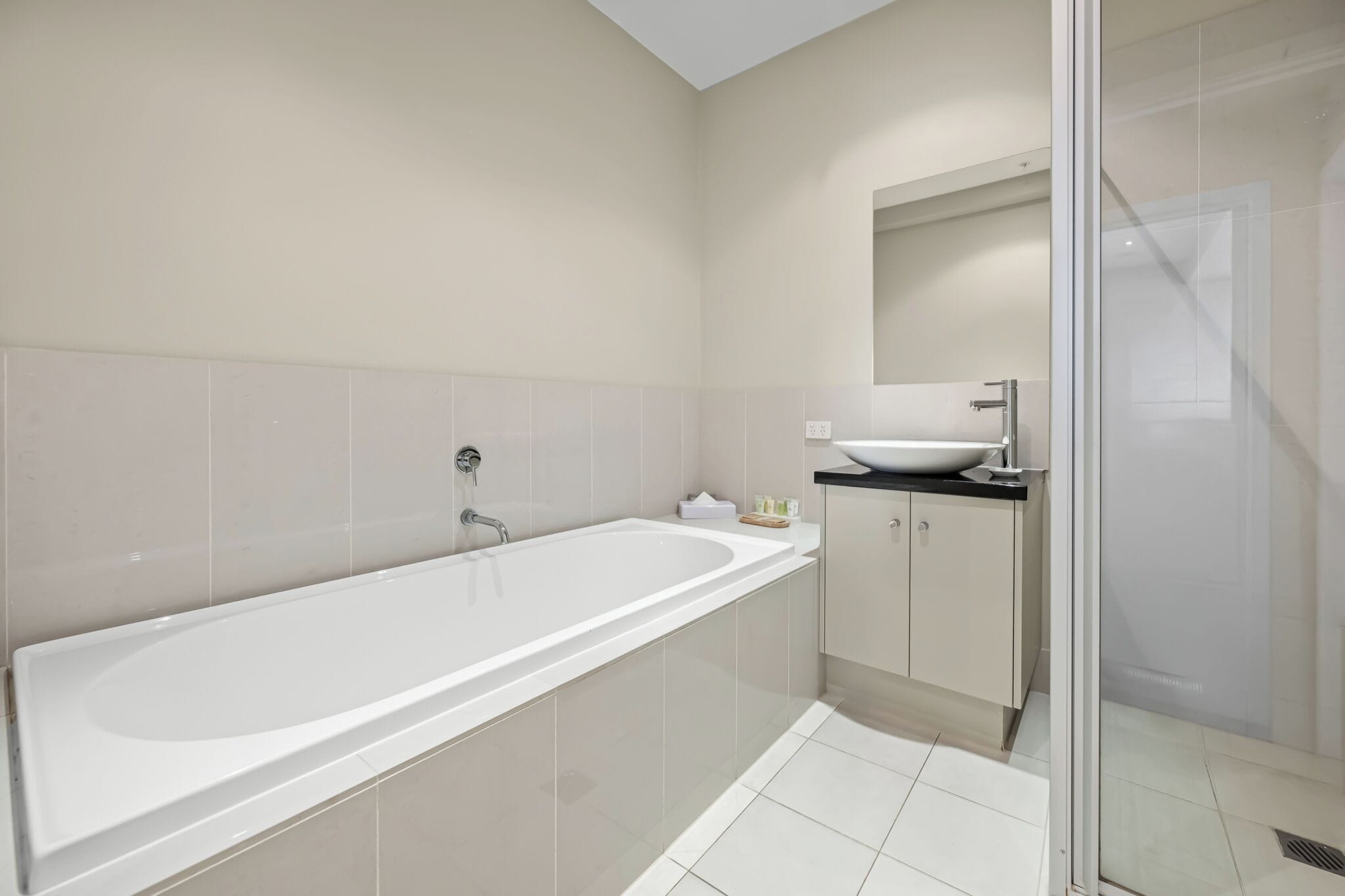 A modern bathroom with a large bathtub, a sink, and a glass shower enclosure.